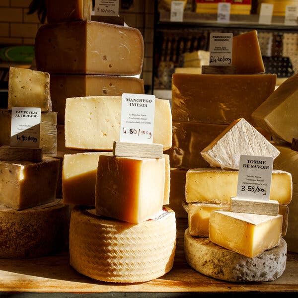An array of cheeses is shown, including one labeled Manchego Inesta and another called Tomme de Savoie. 