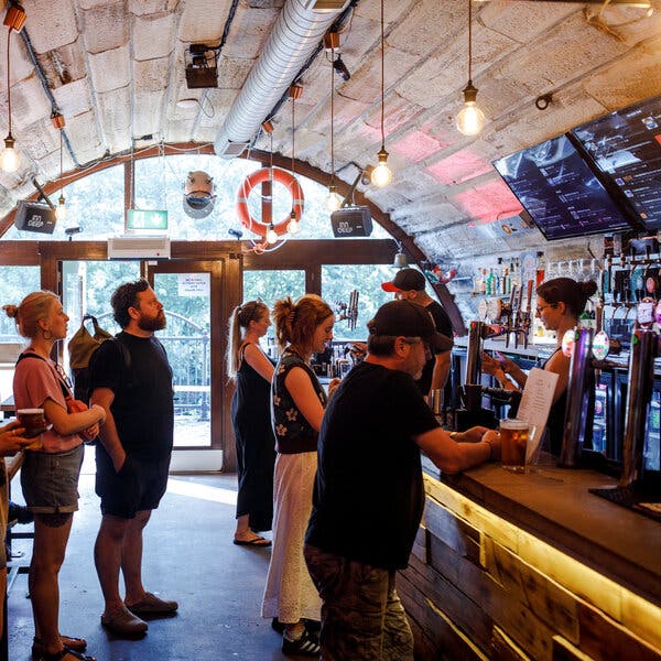 People stand in line at a bar underneath a curved roof. 