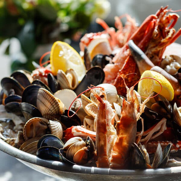 Seen close up, an array of shellfish crowds a plate, including langoustines, mussels and scallops. 